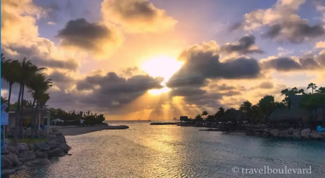 Zonsondergang bij Mambo Beach op Curaçao met de zon die door de wolken op de zee schijnt.
